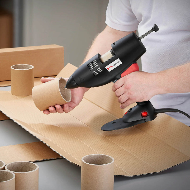 Worker applying TEC Bond 214B hot melt to a cardboard cylinder using a hot glue gun