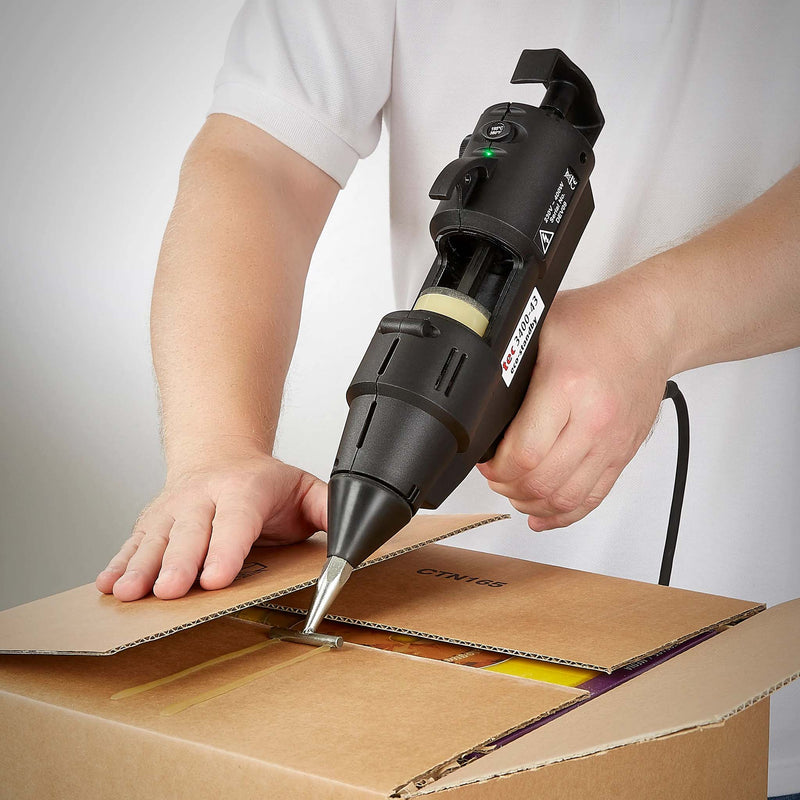 Worker sealing cardboard box using TEC Bond 214B glue slugs with a hot glue gun