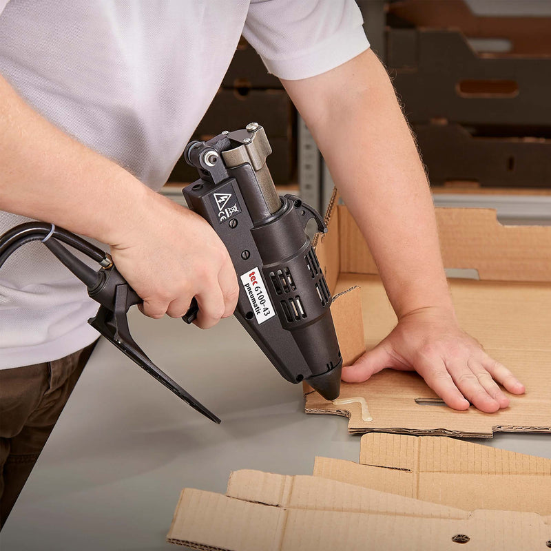 Worker forming a cardboard box using TEC Bond 214B with a hot glue gun