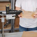 Worker forming a cardboard box using a mounted hot glue gun