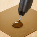 Knottec glue gun dispensing hot adhesive onto a non-stick silicone mat for woodworking applications.