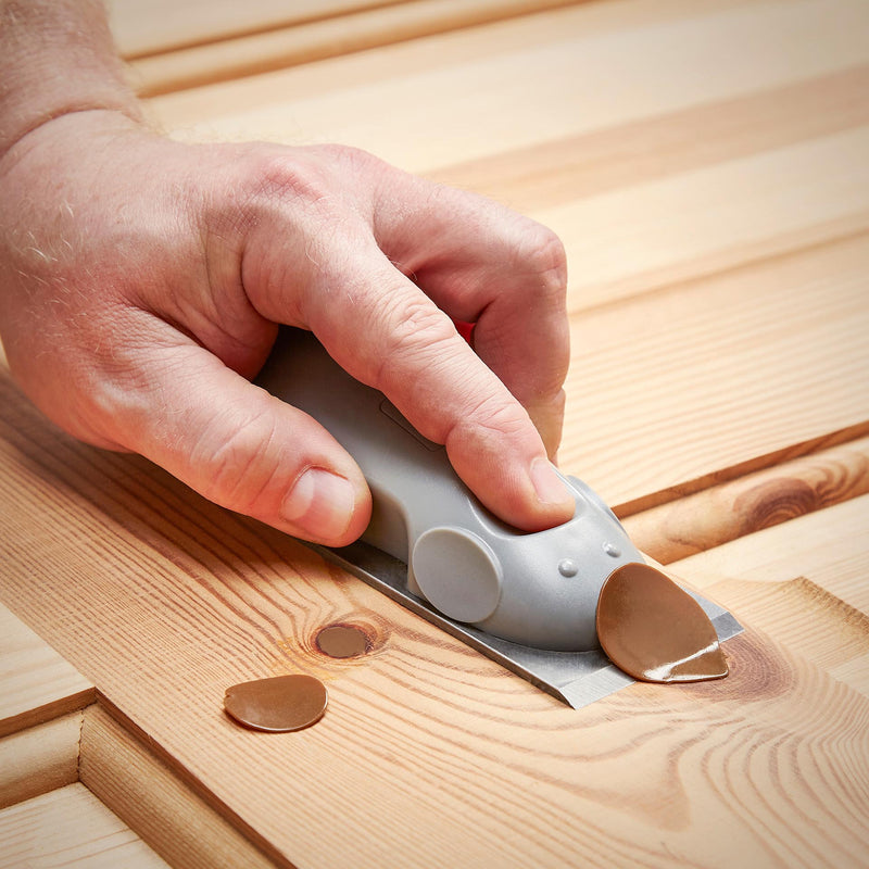 Person using the Mouseplane tool to trim and level a cured adhesive repair on a wooden surface.